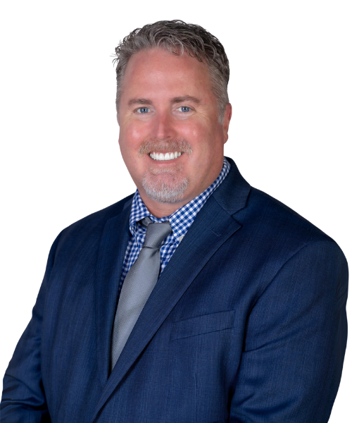 Smiling consultant with short, light hair and a trimmed beard, wearing a dark blue suit, checkered shirt, and gray tie, posing against a white background.
