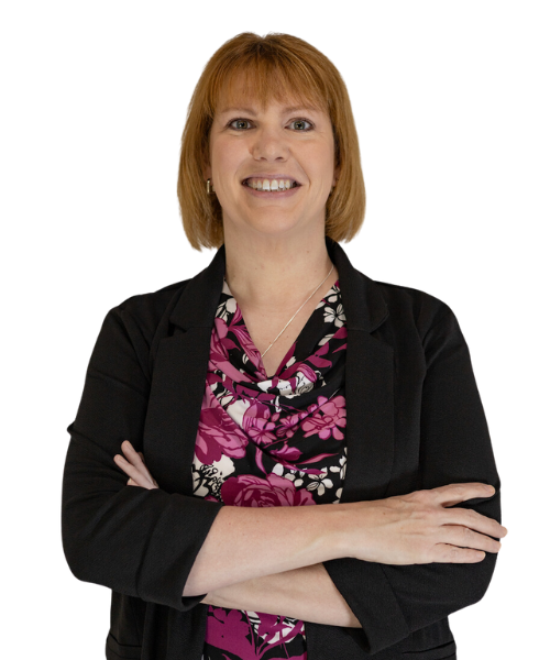 A smiling consultant with short light brown hair stands with arms crossed, wearing a black blazer over a floral-patterned blouse featuring shades of pink, white, and black.
